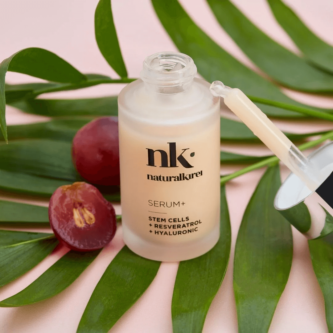 NK Serum+ organic skincare product featuring resveratrol and hyaluronic acid on green leaves.